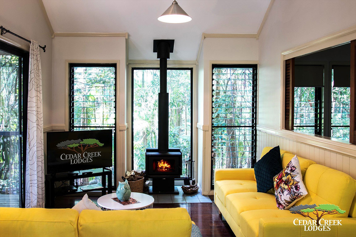 Homely creek lodge with brightly coloured futniture & the fireplace burning.