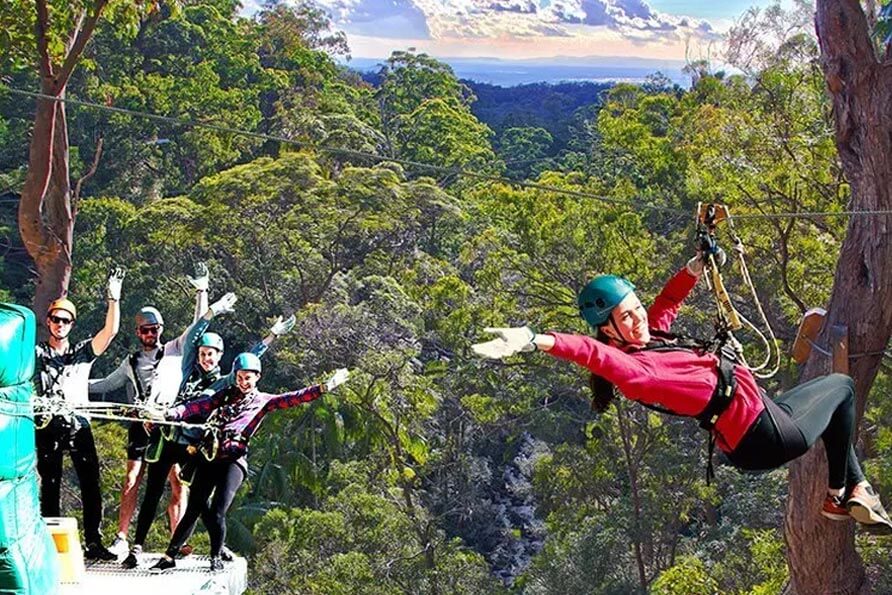 Treetop Challege - group watches on as a woman flies down the zipline